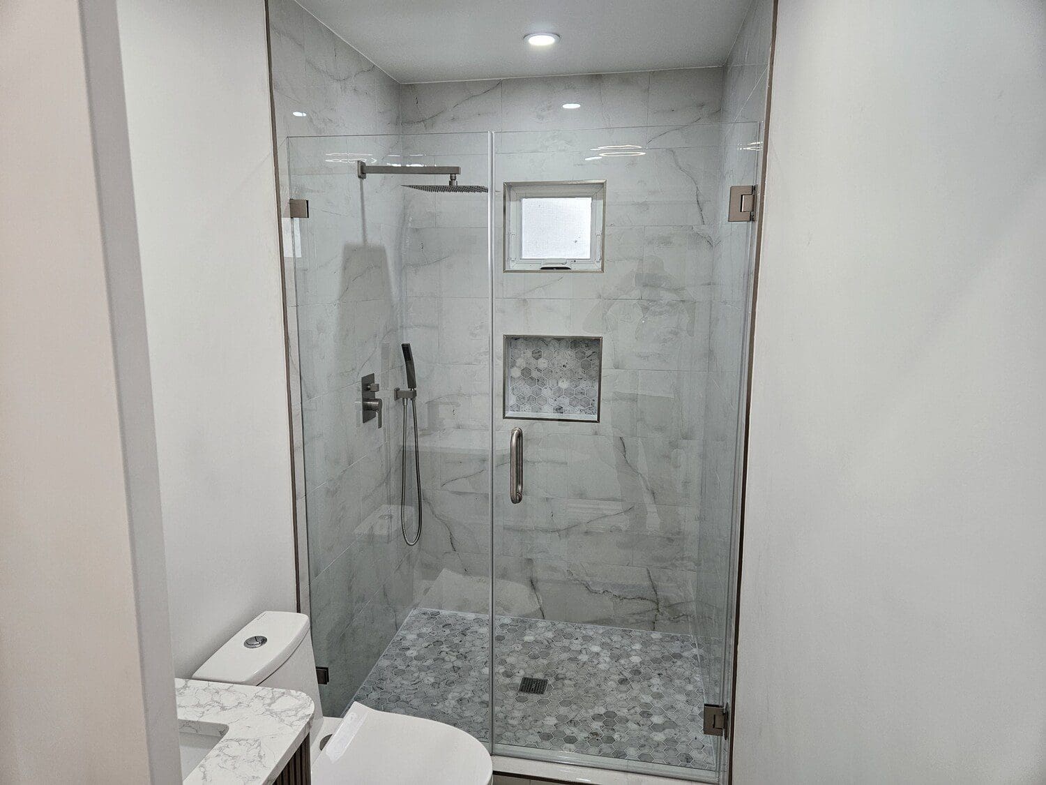 A bathroom with a walk in shower and tiled floor.