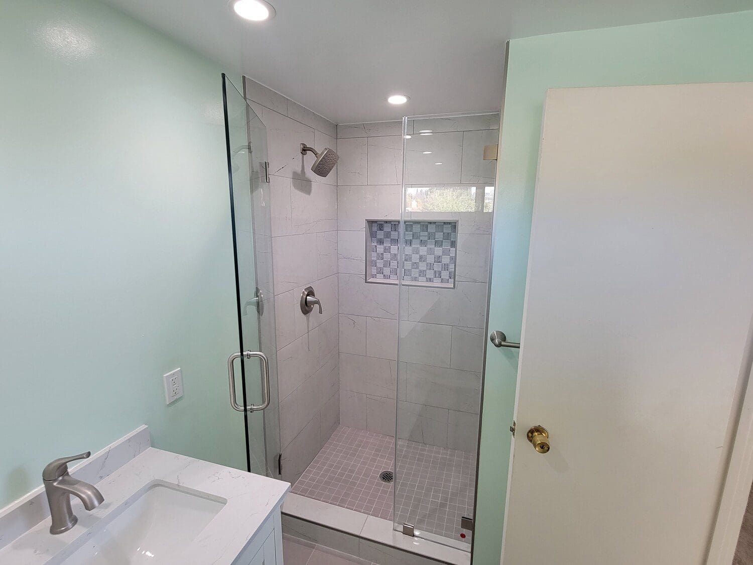 A bathroom with a sink, mirror and shower.