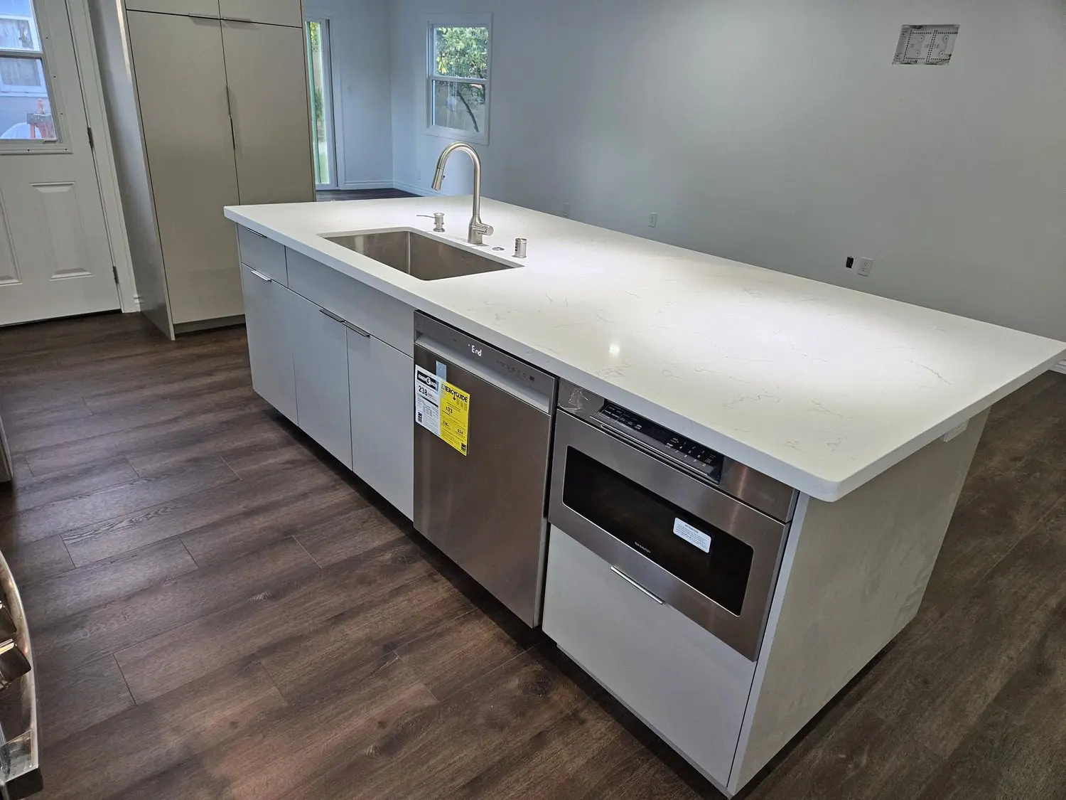 A kitchen with white counters and wooden floors.