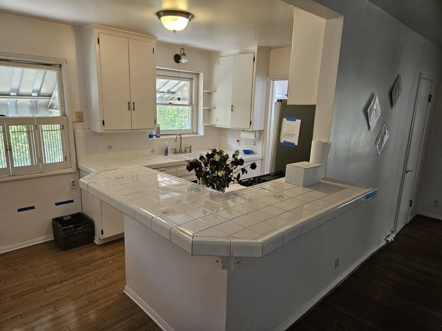 A kitchen with white cabinets and wooden floors.