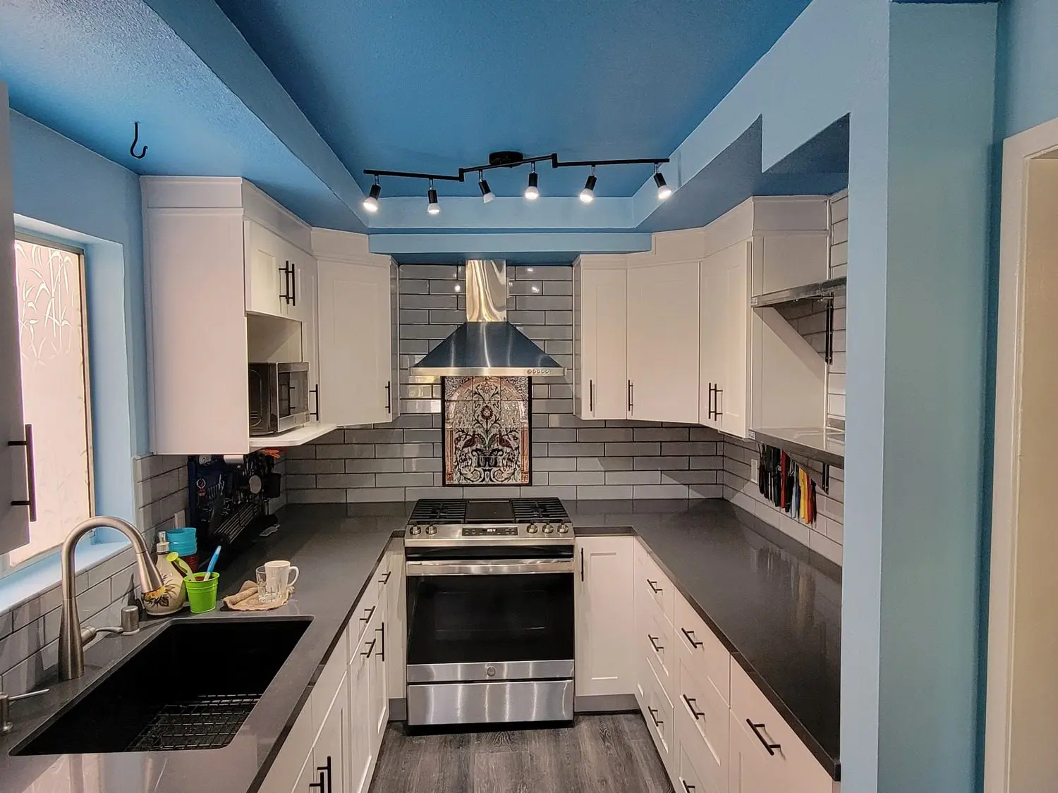 A kitchen with white cabinets and black counter tops.