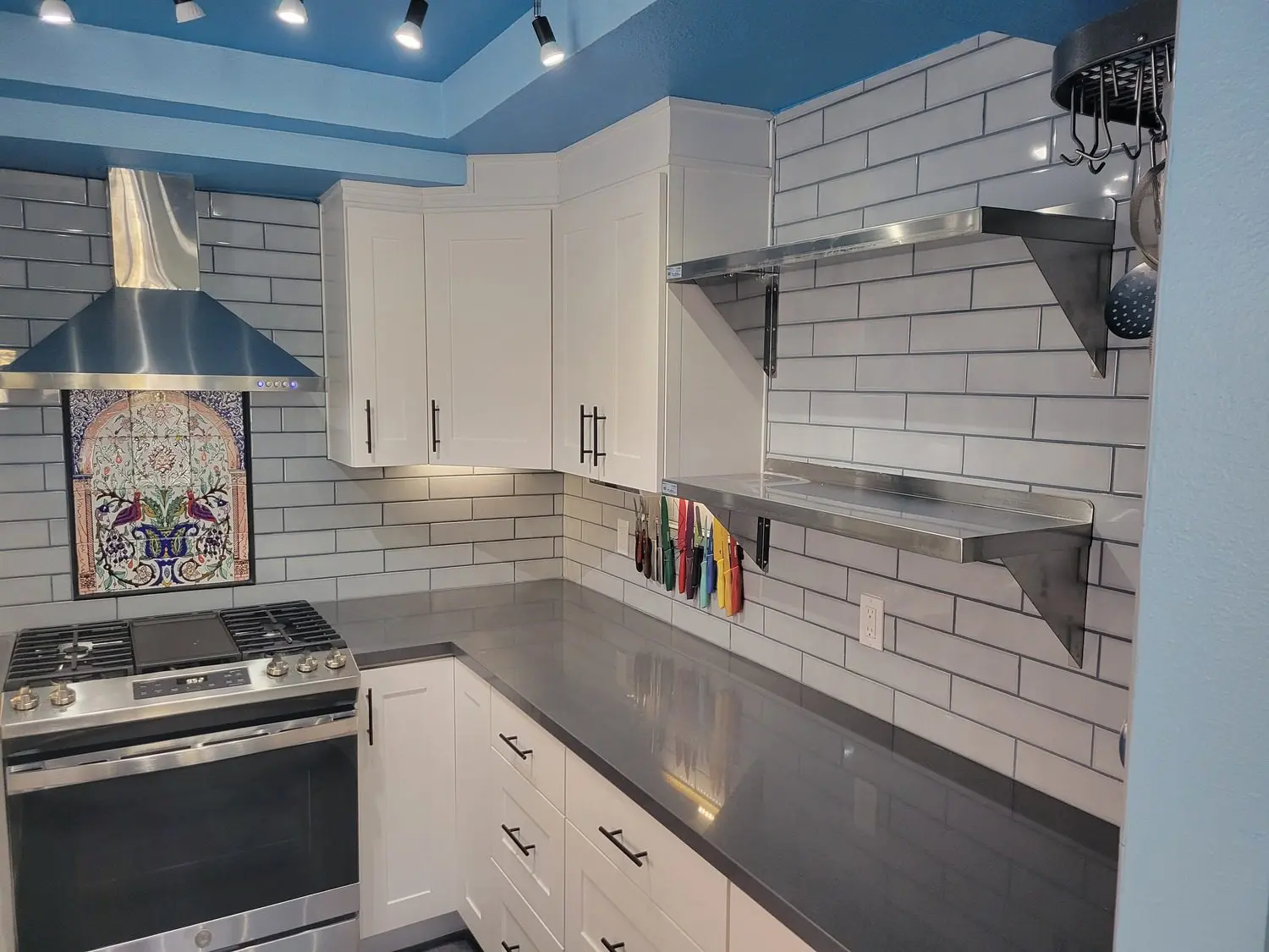 A kitchen with white cabinets and blue ceiling