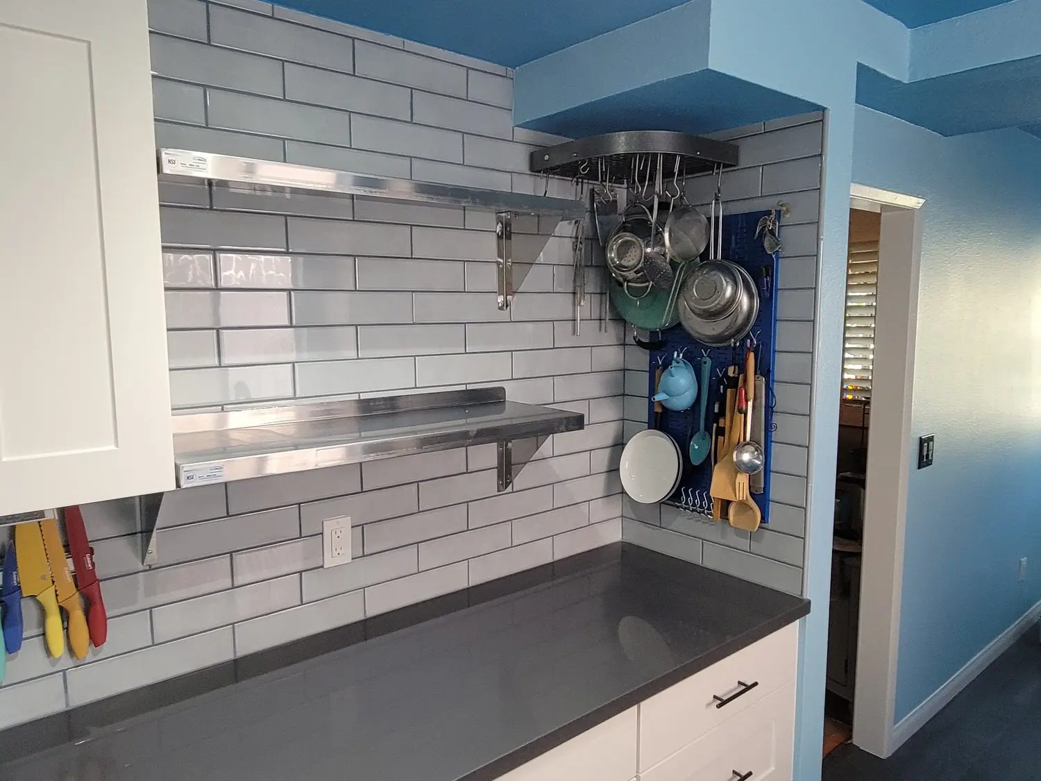 A kitchen with white cabinets and blue walls.