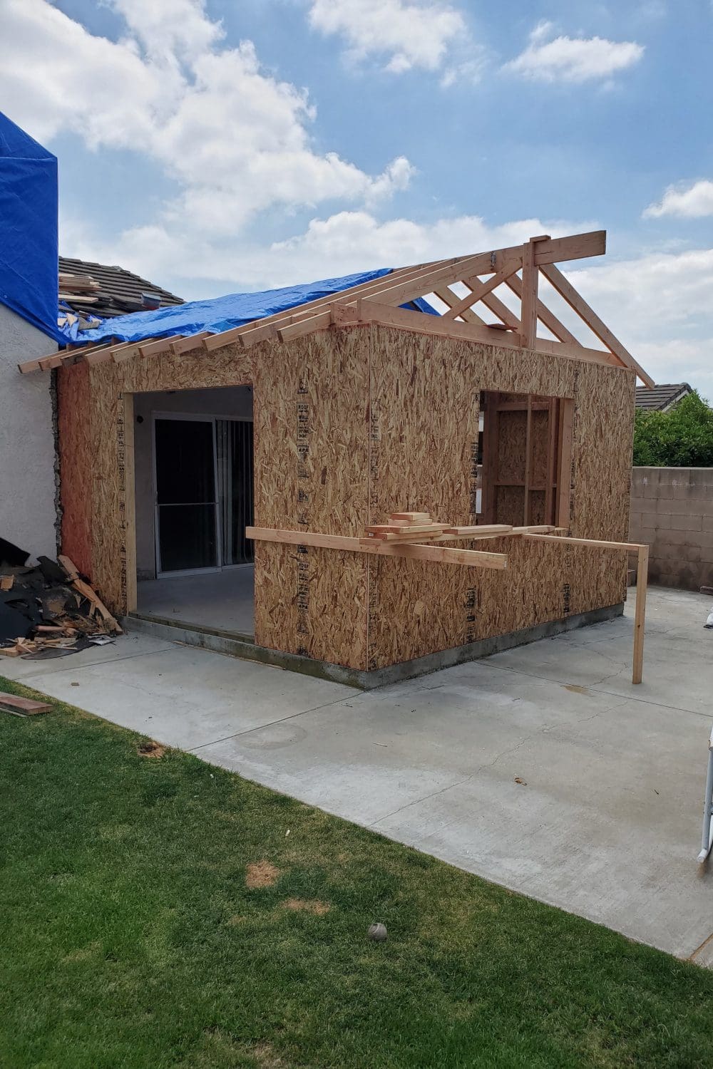 A house being built with wood and blue tarp.