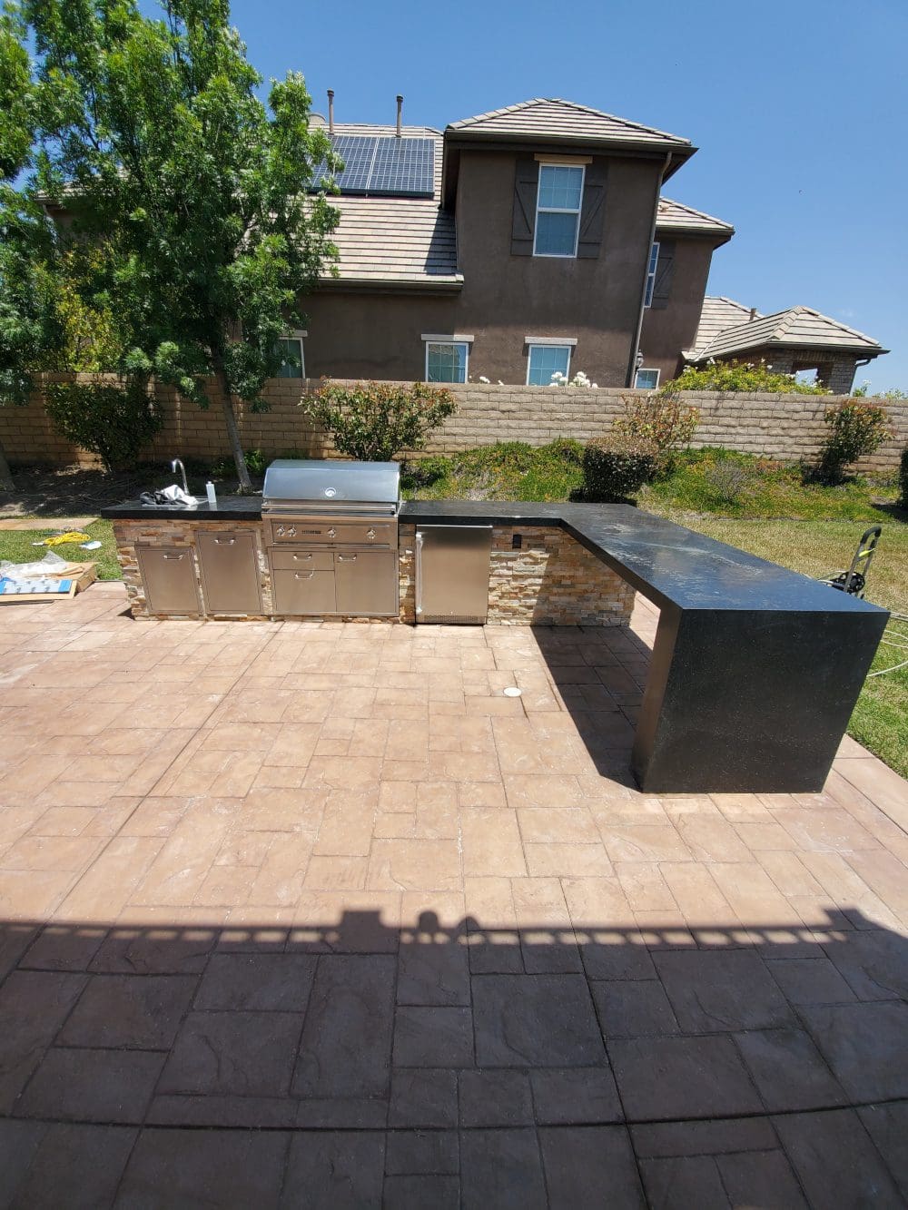 A backyard with an outdoor kitchen and bbq.