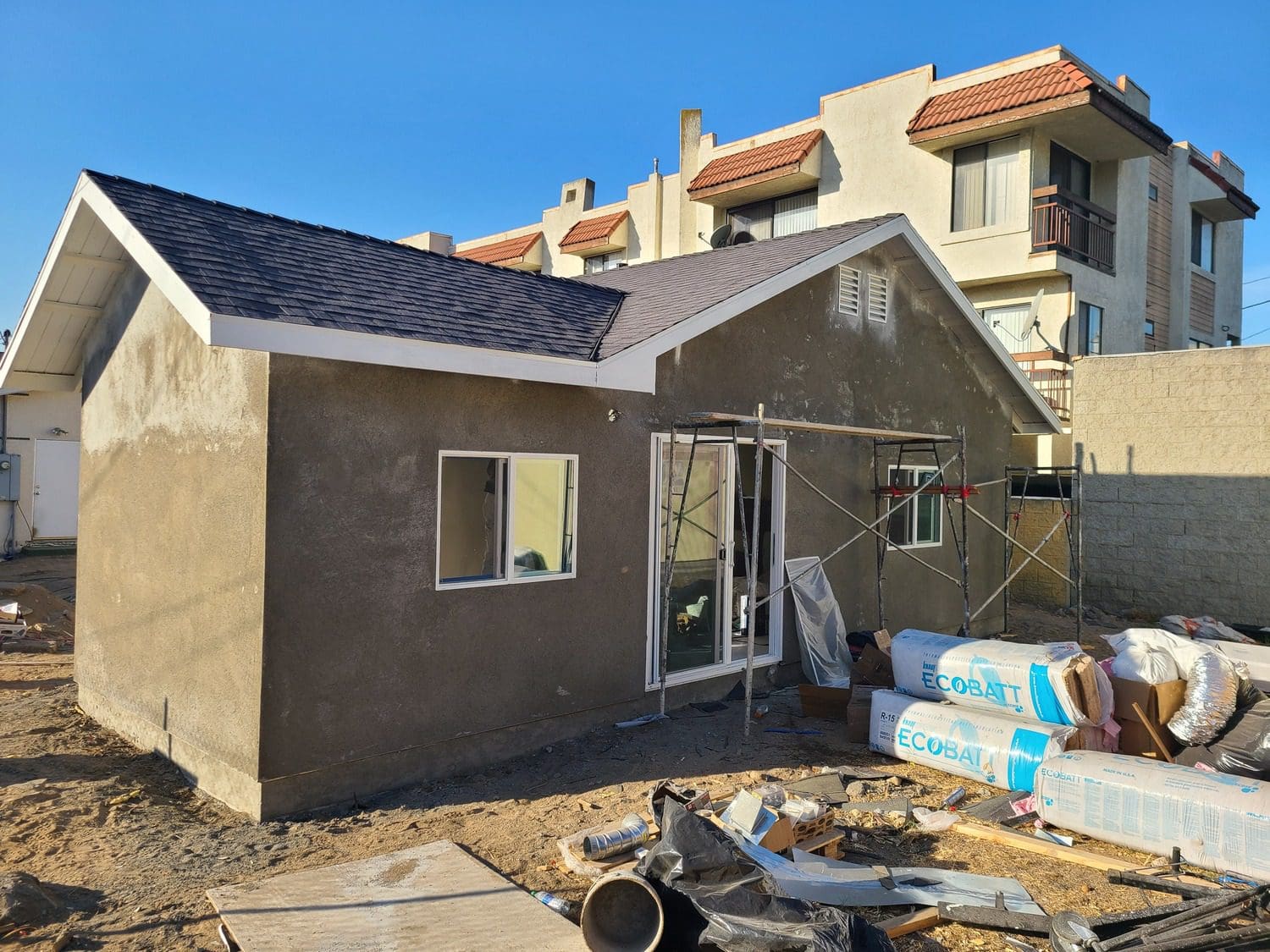 A house being built with construction materials on the ground.