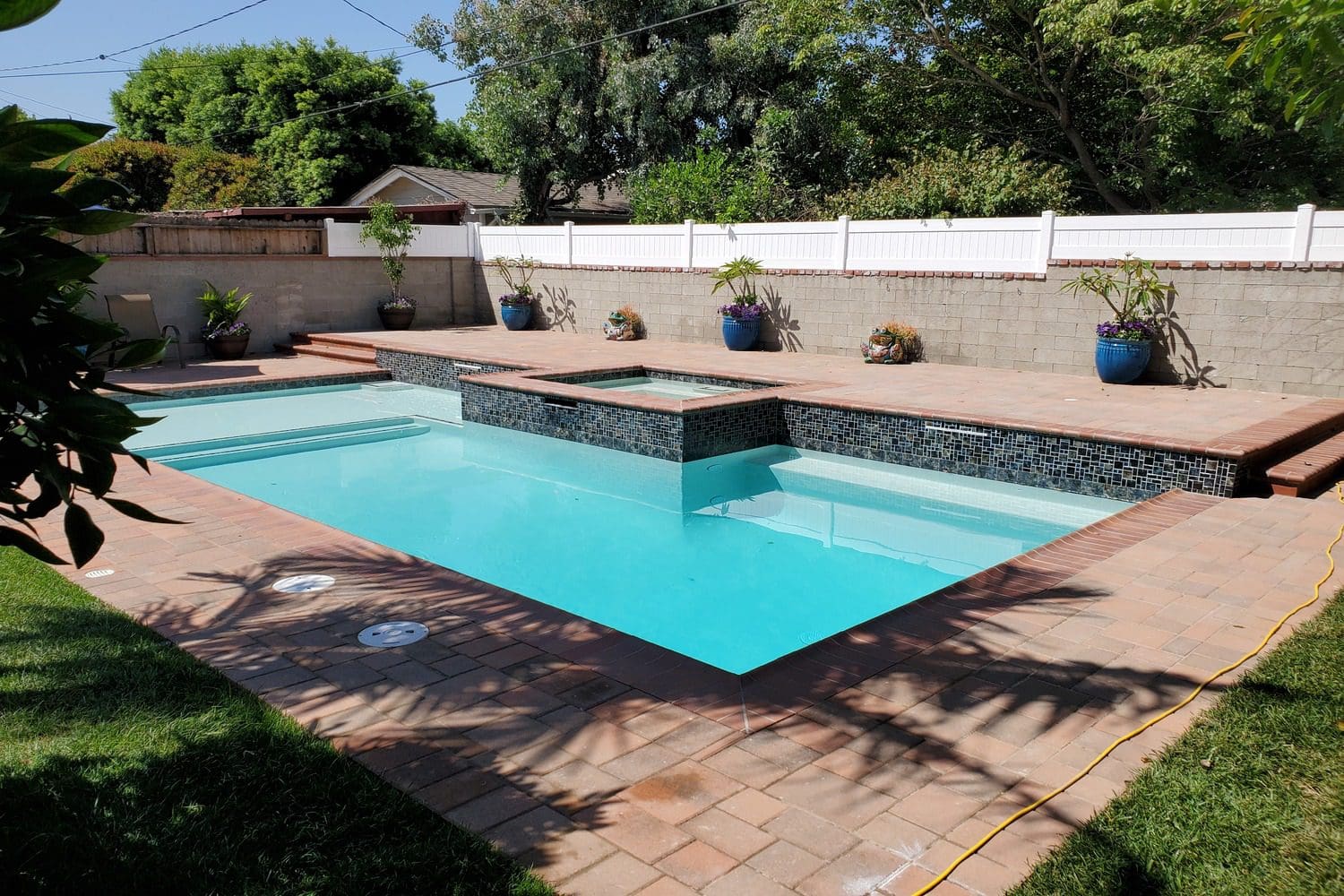 A pool with a stone wall and a brick floor