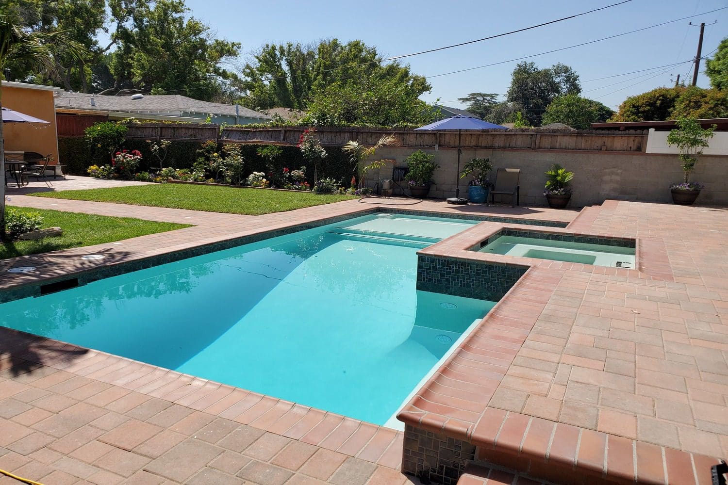 A pool with a bench and a hot tub in it.