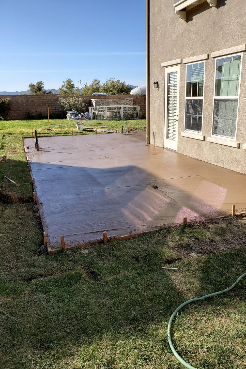 A patio with cement on the ground and grass.