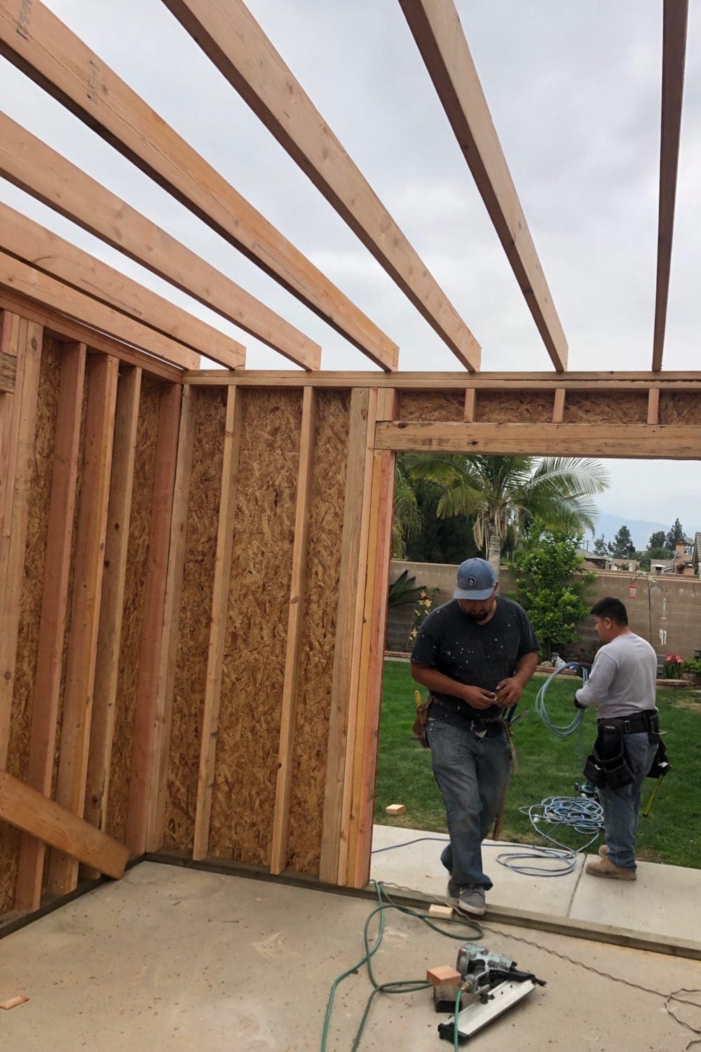 Two men are working on a house under construction.